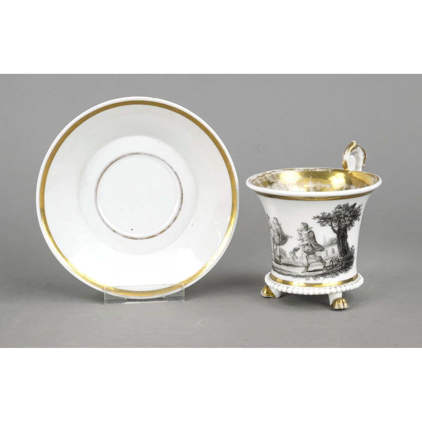 Biedermeier cup with saucer, arou: Biedermeier cup with saucer, around 1840, calathos form with rosette handle on lion feet, black lot painting on the front with gallant scene, ornamental gilding, rubbed, UT Mariage, h. 11 cm