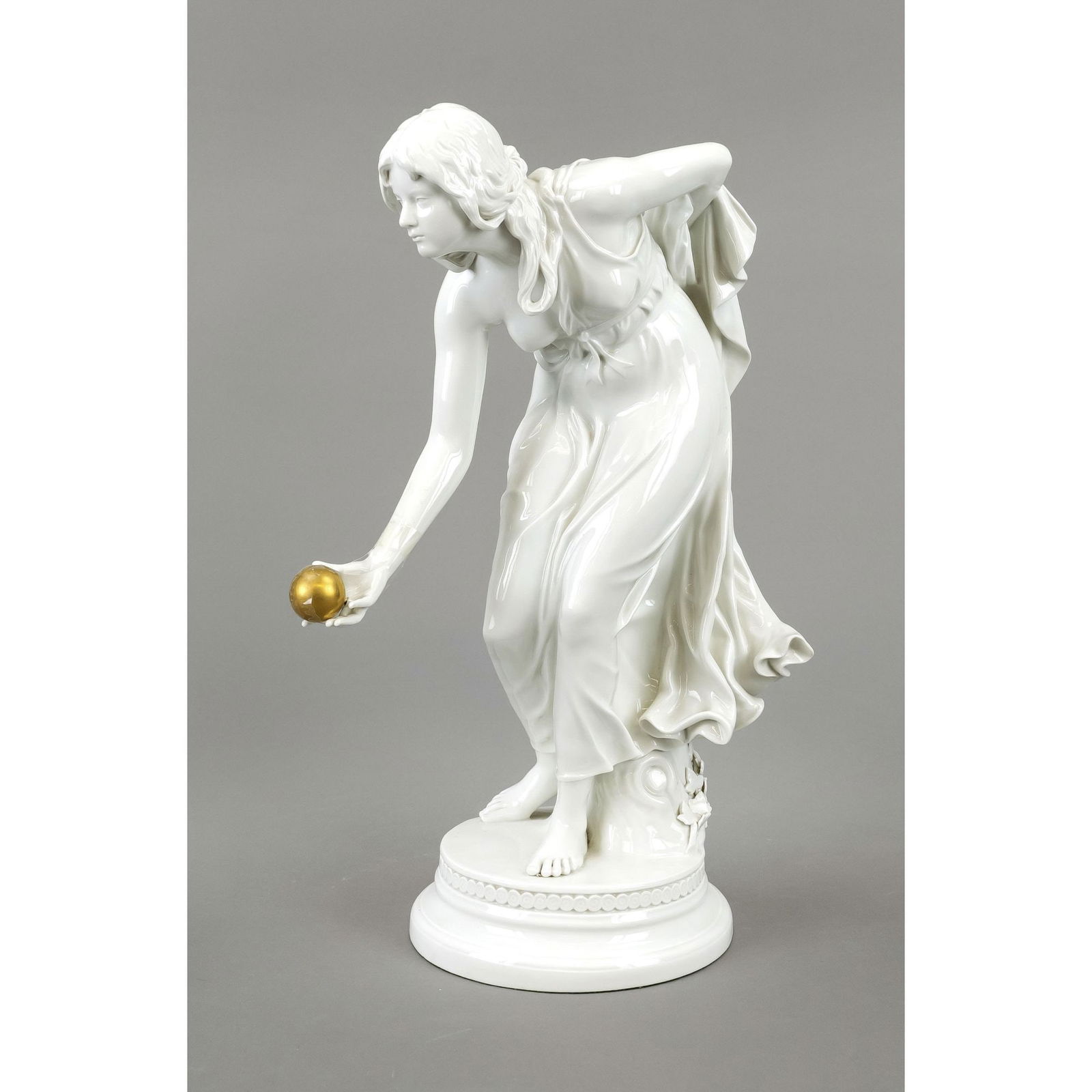 The ball player. Meissen, 1st choi: The ball player. Meissen, 1st choice. 1980s. Designed by Walter Schott (1861 Ilsenburg - 1938 Berlin) in 1897, a girl in a long robe standing on a round base in a bent posture, holding a golden ball i