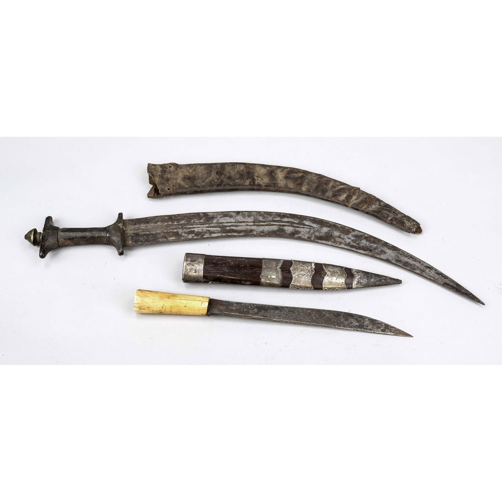 Dagger and scimitar, 19th/20th c: Dagger and scimitar, 19th/20th century Scimitar cut on both sides with double fullers, horn hilt elements (loose), brass pommel. Simple leather scabbard, tip missing and worn, l. 63 cm Also a dagger k