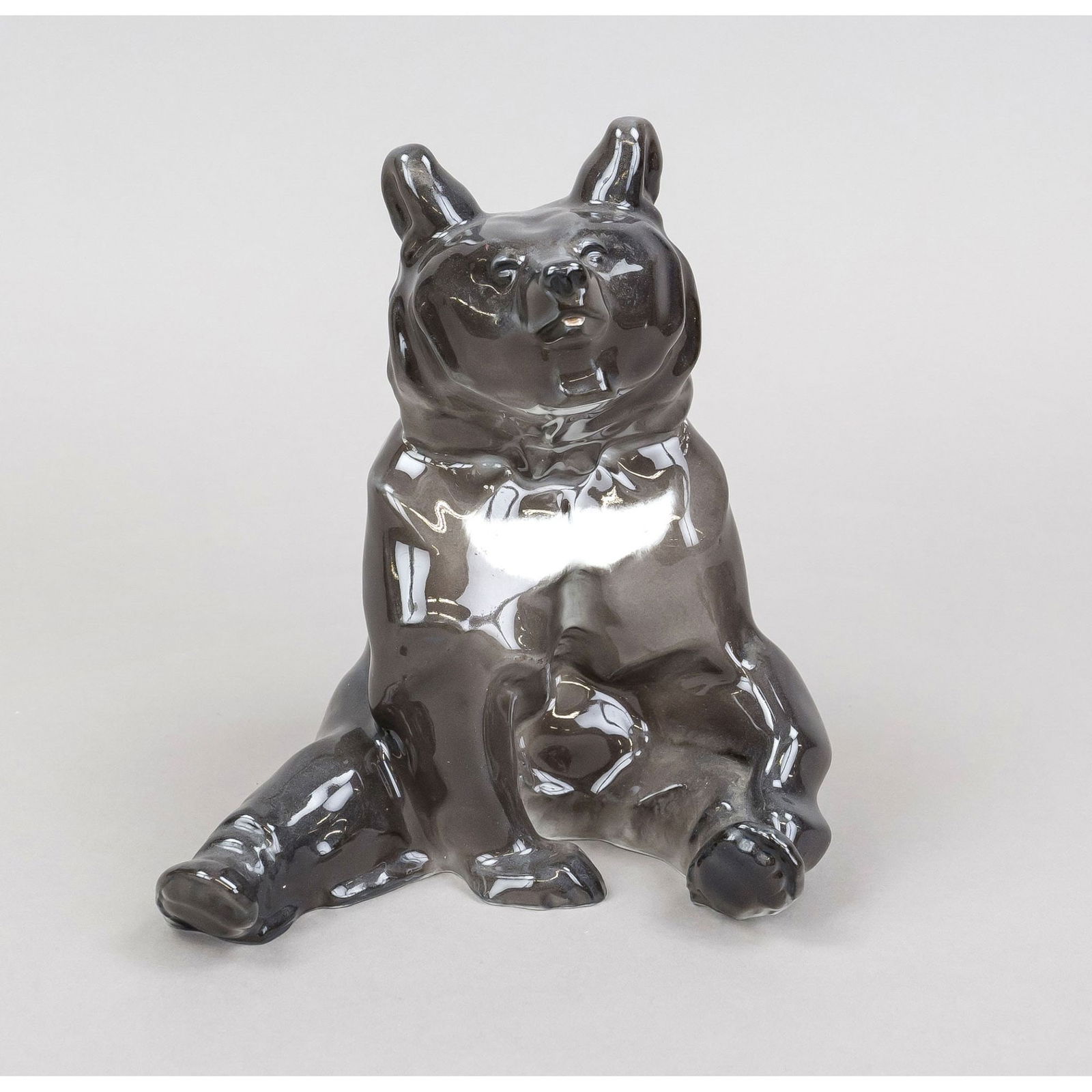 A seated collar bear, KPM Berlin,: A seated collar bear, KPM Berlin, mark 1870-1945, 1st choice, year mark for 1924, blue imperial orb mark, designed by Anton Puchegger in 1909, painted in underglaze colors, partially rubbed, h. 19.5 c