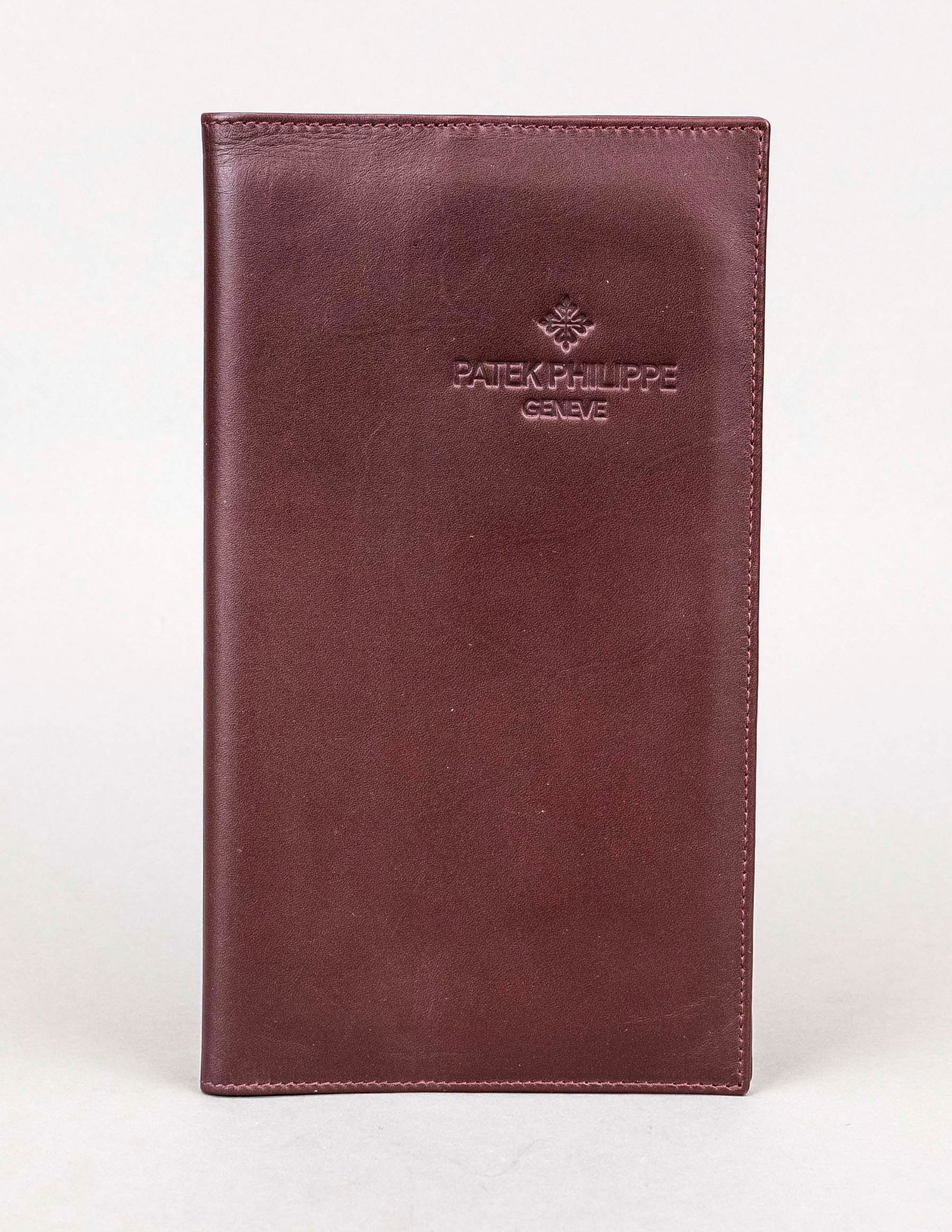 Patek Philippe, large-format wallet/do: Patek Philippe, large-format wallet/document cover, aubergine-colored leather, portrait format with flap, embossed logo on the front, sand-colored velour interior with two compartments, slight signs o