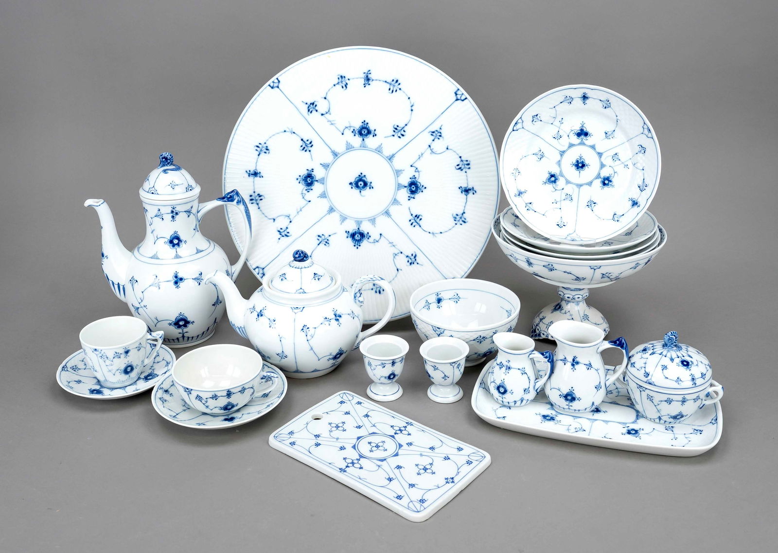 H. 7.5 cm, 1 teapot, chipped, H.: H. 7.5 cm, 1 teapot, chipped, H. 16 cm, 7 teacups with 8 saucers, H. 6 cm, milk, sugar and cream on tray, L. 26 cm, 3 cereal bowls, Ø 13 cm, 1 footed bowl, Ø 22 cm, 11 egg cups, H. 6 cm, plus 6 brea