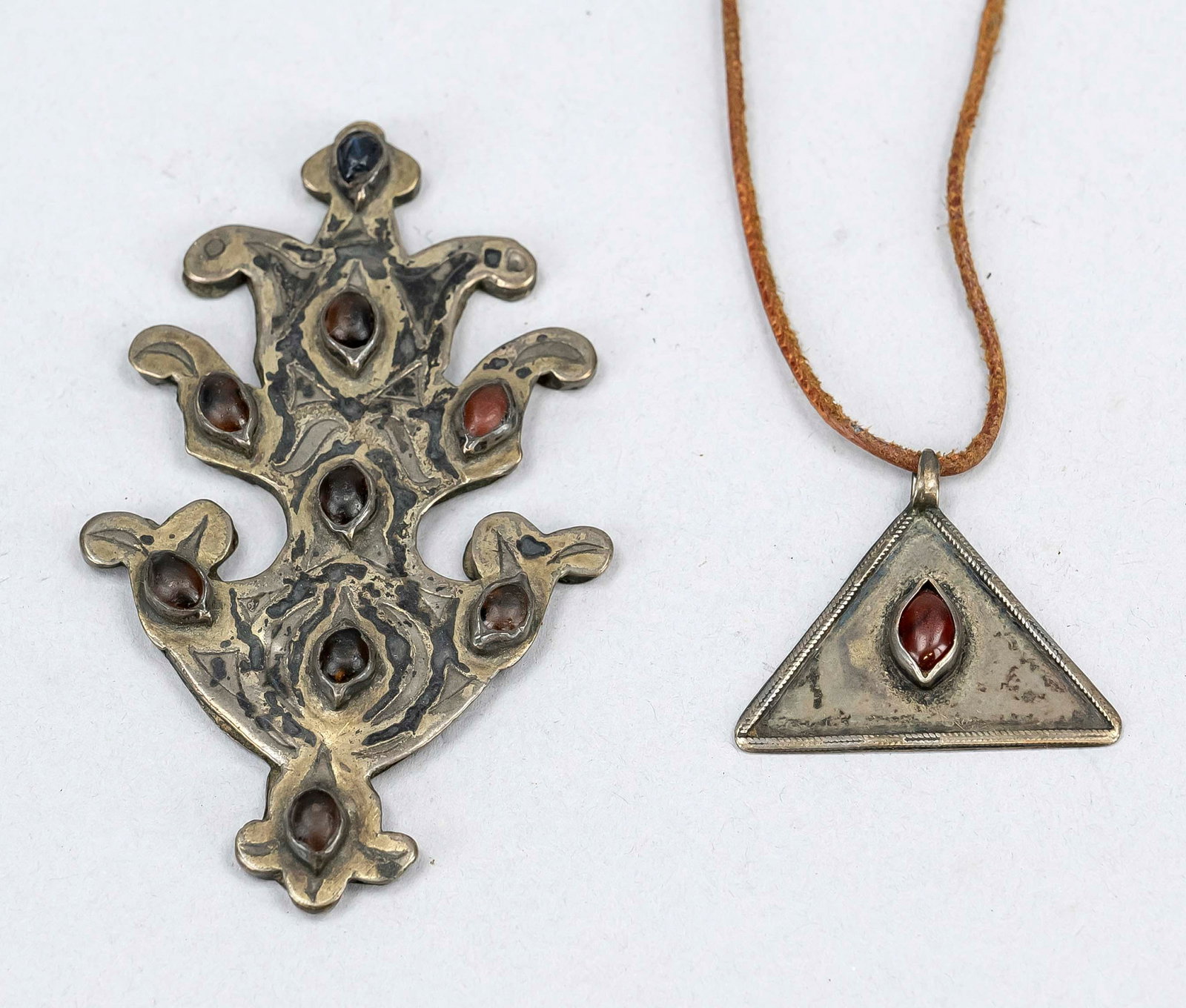 2 Tumar pendants, Turkmenistan 19: 2 Tumar pendants, Turkmenistan 19th century, silver-gilt (rubbed) with gemstone setting. The larger one without eyelet, reverse with small missing part. L. up to 8.5 cm