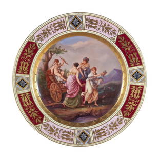 Royal Vienna Hand Painted Triumph des Amor Porcelain: Royal Vienna hand painted porcelain plate depicting a scene with three women pulling cupid on a chariot. Has gilded rim with floral scrolls. Titled Amors Triumph on verso, and blue underglaze crown