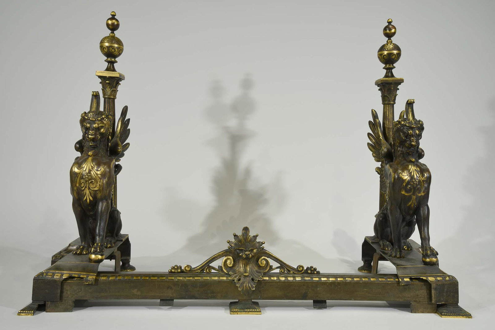 Antique Gilt Bronze Andirons in the form of Griffins: Comprised of two andirons and bottom screen spacer. Late 19th century. Length 32in x Height 25in x Depth 13in. Griffins are width 6in x Height 25in x Depth 13in