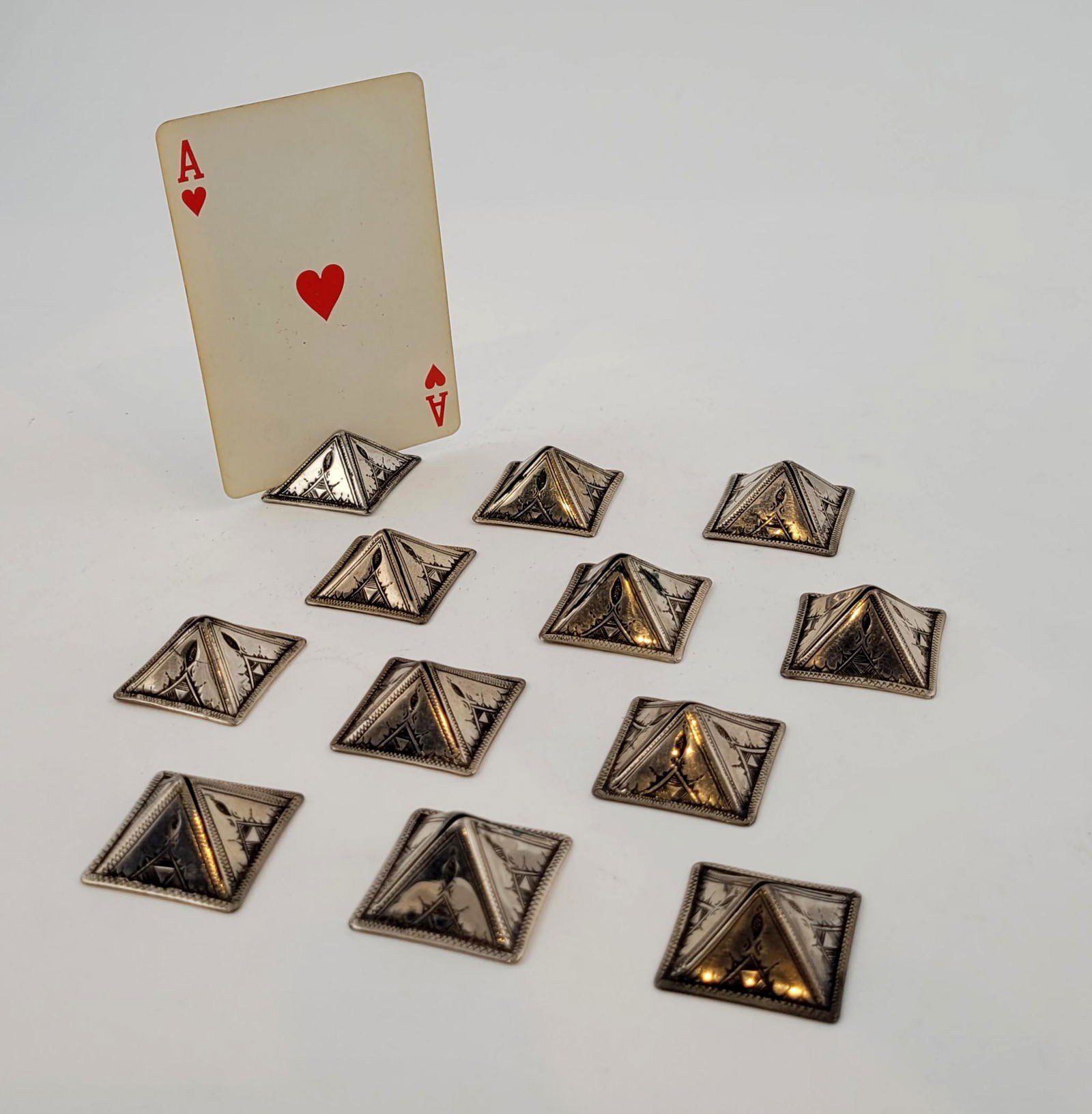 Set of Twelve Niello Silver Card Holders: Twelve Niello silver place card holders, each in pyramid form with incised design. 1 1/8 x 1 1/8 inch each. weight 55 grams Property from the estate of Dr. Nafis Sadik, no reserve.