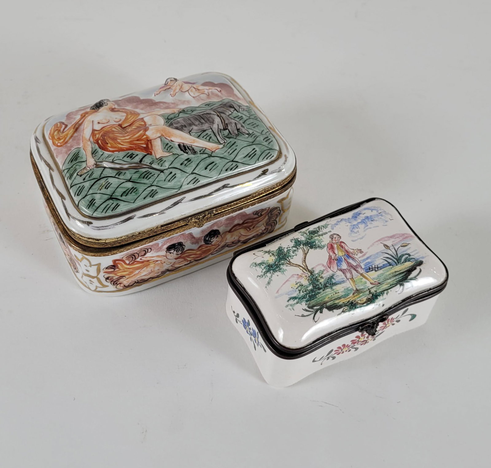A Capo Di Monte Ceramic Box & Enamel Box: Two Boxes, one Capo Di Monte (Nude in a field with angel) and another enameled with man in a landscape. 4 1/2 x 3 1/2 x 2 inches largest.
