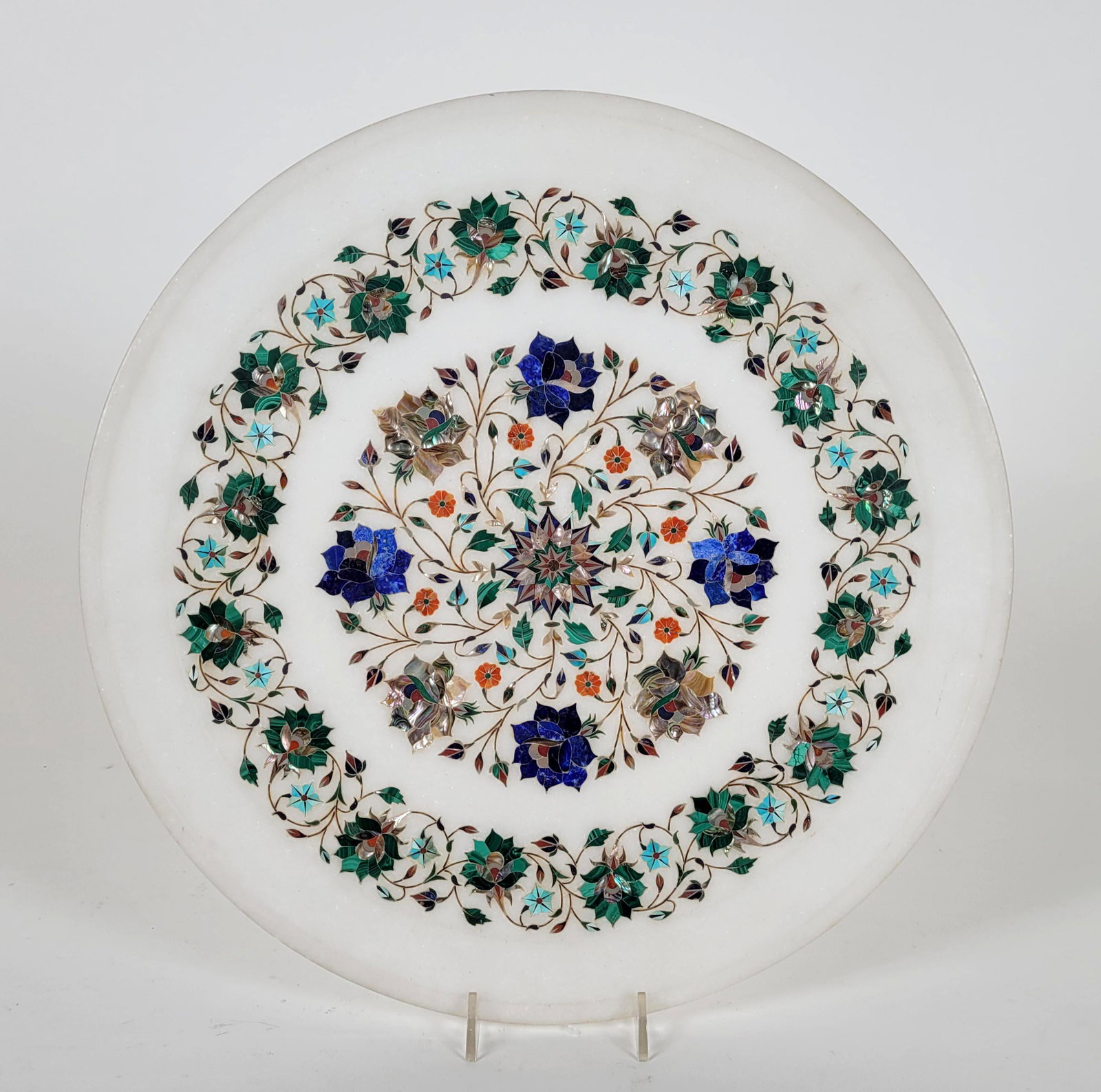 An Indian Pietra Dura Inlaid Charger: An Indian pietrs dura inlaid charger inlaid with Lapis Lazuli carnelian Turquoise, Marcasite and mother of pearl. Diameter: 14 1/4 inches. Property from the estate of Dr. Nafis Sadik, no reserve.