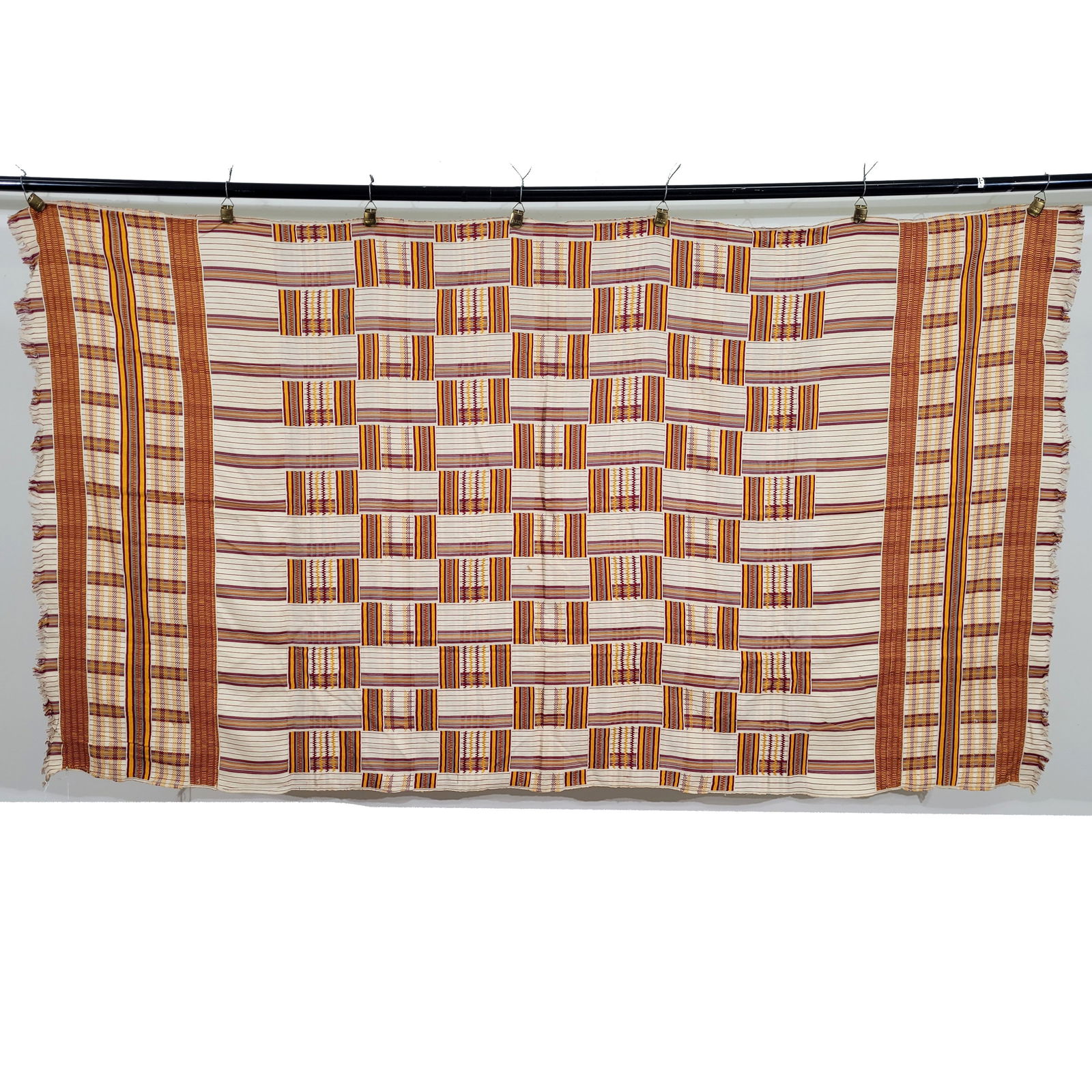 West African Silk Kente Cloth: West African silk kente cloth. In a traditional, basket-like pattern marigold and maroon silk threads are stitched into bands and hatched lines. Fringes on the end. Intact. Dimensions: 43 x 78 inches.