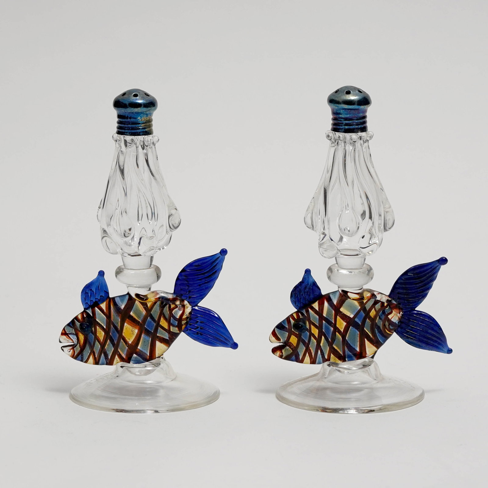 Pair of Murano Glass Fish-Form Salt and Pepper Shakers: Pair of Murano glass salt and pepper shakers, each with clear blown glass stem above a colorful applied fish-form body with blue fins, raised on circular foot, with pierced metal caps. Signed . H: 4 3