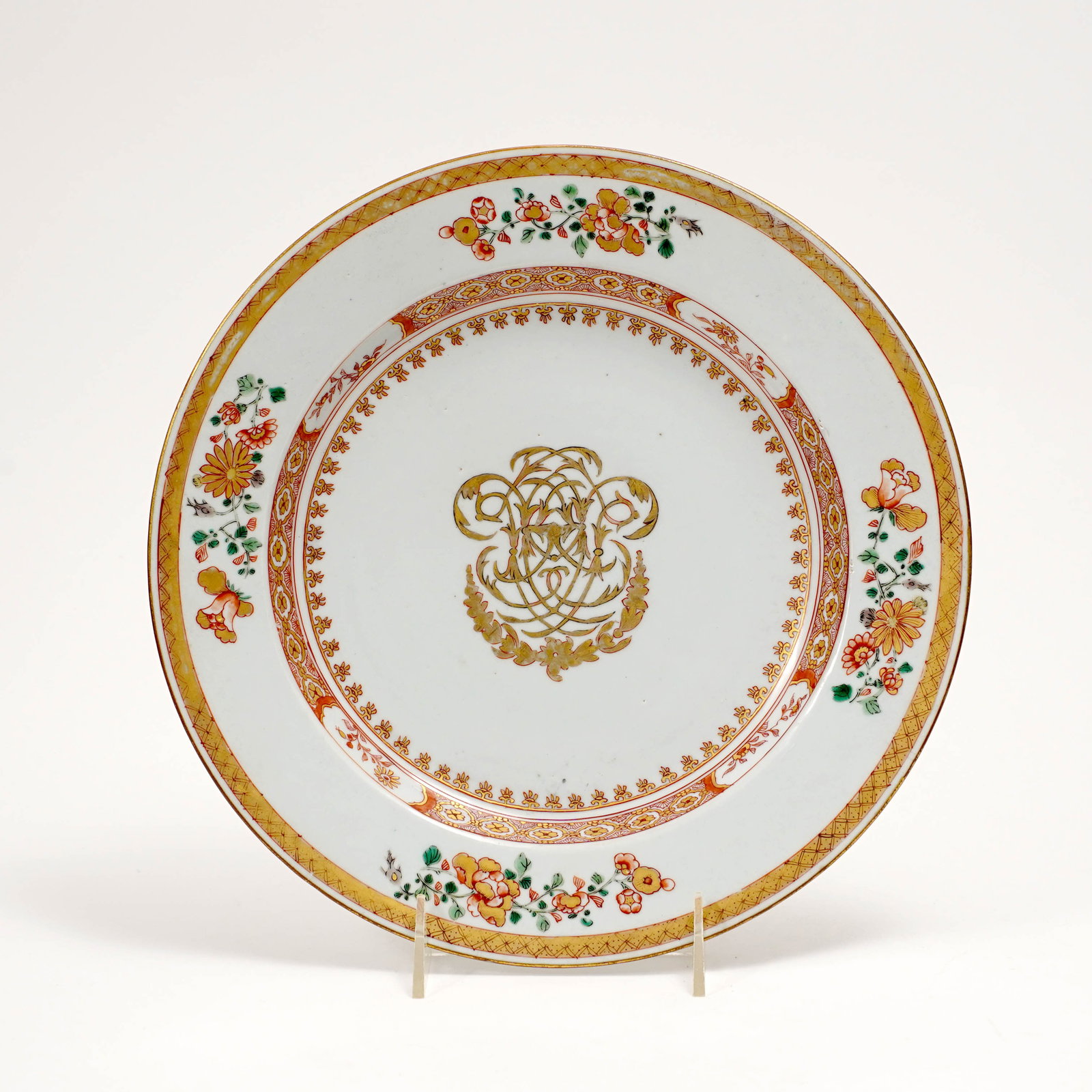 Chinese Export Porcelain Armorial Plate: Chinese export porcelain plate with gilt armorial-style monogram to the center, surrounded by gilt and iron-red borders, with floral sprays to the rim and gilt diaper-pattern edge. Qing dynasty style,