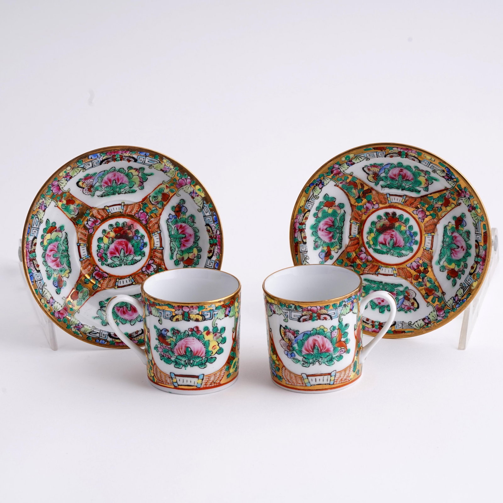 Pair of Chinese Famille Rose Tea Cups and Saucers: A pair of Chinese porcelain tea cups and saucers, decorated in famille rose palette with floral medallions, butterflies, and gilt borders. Each cup and saucer with iron-red seal mark to underside read