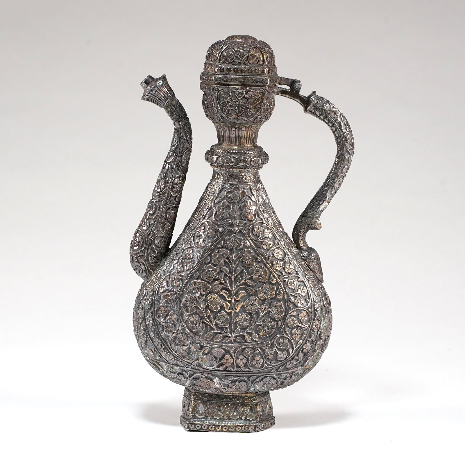 Large Indian Repoussé Silver Ewer: Large Indian repoussé silver ewer, late 19th/early 20th century, of pear-shaped form with hinged domed cover, curved spout, arched handle, and short circular foot. The body finely chased and repouss�