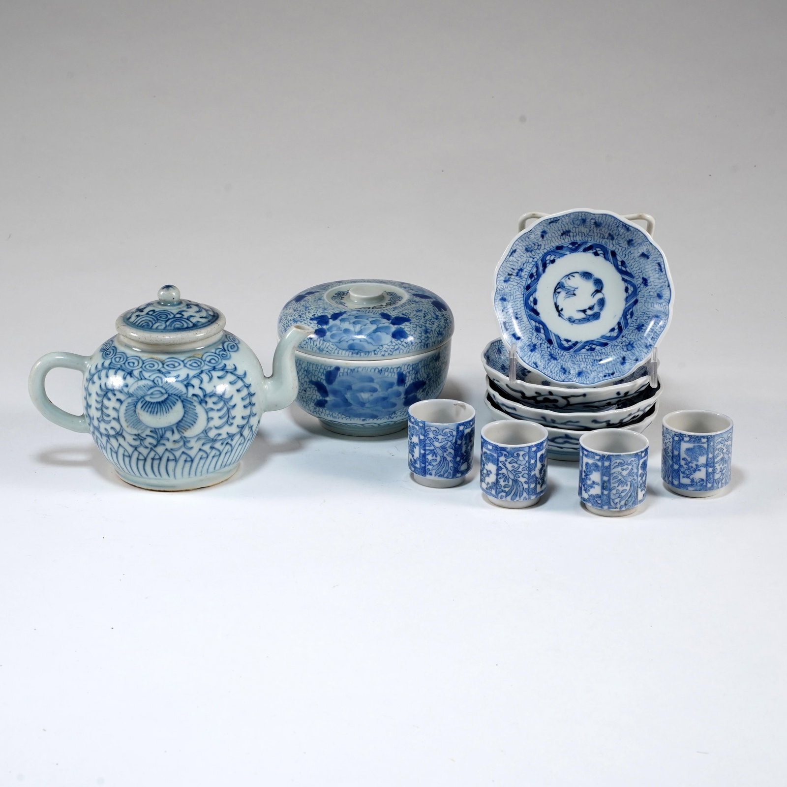 Japanese Blue and White Porcelain Tea Set: Japanese blue and white porcelain tea set, comprising lidded teapot, covered bowl, four cups, and small scalloped dishes, decorated with floral and foliate underglaze blue designs. Size for cup: H: 1