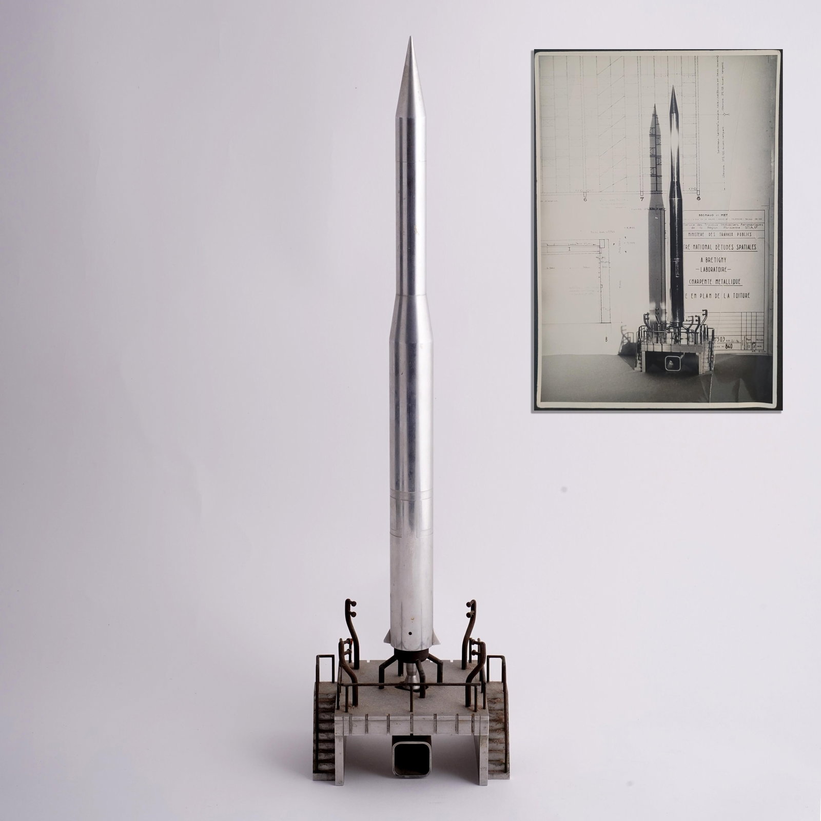 French Space Program Rocket Model with Architectural Presentation Photograph, circa 1961–1965: A rare and visually compelling grouping comprising a mid-20th century French aerospace presentation model of a slender sounding rocket, accompanied by a period black-and-white photograph depicting the