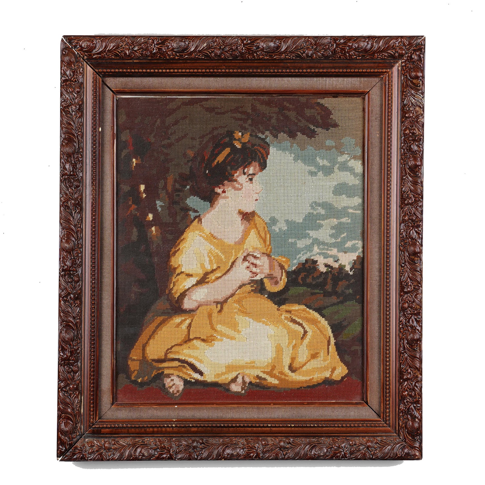 Framed Needlepoint After a Classical Portrait: A framed needlepoint picture depicting a seated young woman in a yellow dress, shown in a wooded landscape holding a small object in her hands. Worked in colored wool or thread on canvas, after an