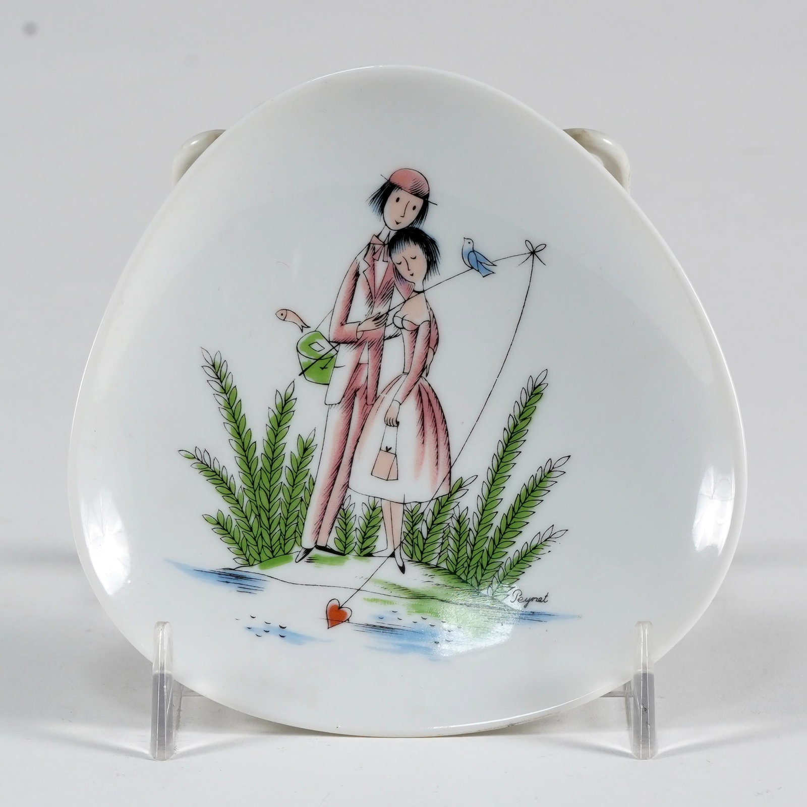 Rosenthal Porcelain Lovers Plate / Dish: Rosenthal porcelain dish, rounded triangular form, decorated with Raymond Peynet-style lovers, birds, foliage, and heart-form kite motif, signed “Peynet” in the design. L: 4 1/2 x W: 4 1/2 x