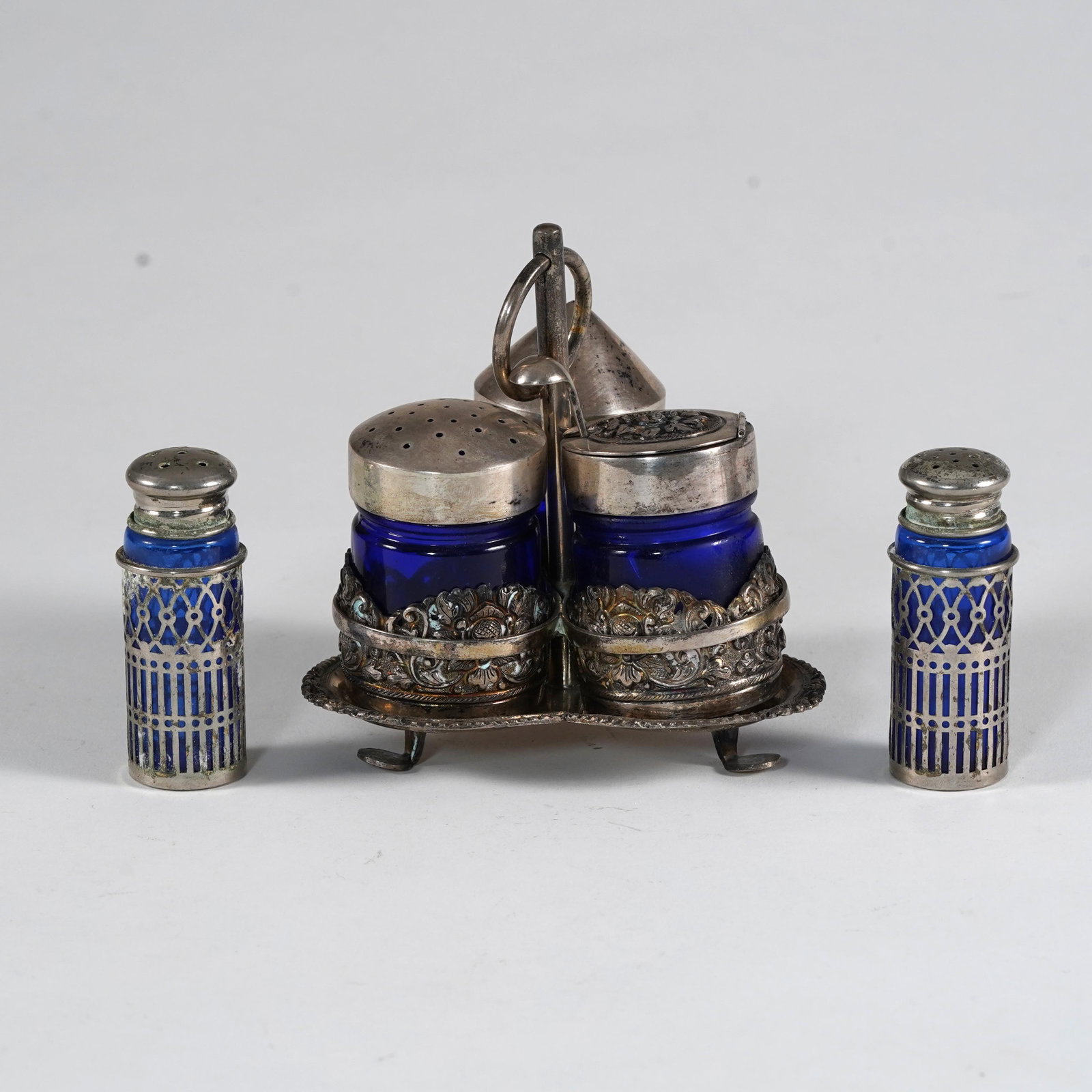 MRH 800 Japan Silver-Mounted Cobalt Glass Condiment Set: A Japanese 800 silver-mounted cobalt blue glass condiment set, marked MRH 800 Japan, comprising a fitted silver stand with ring handle and three cobalt glass condiment jars, together with two