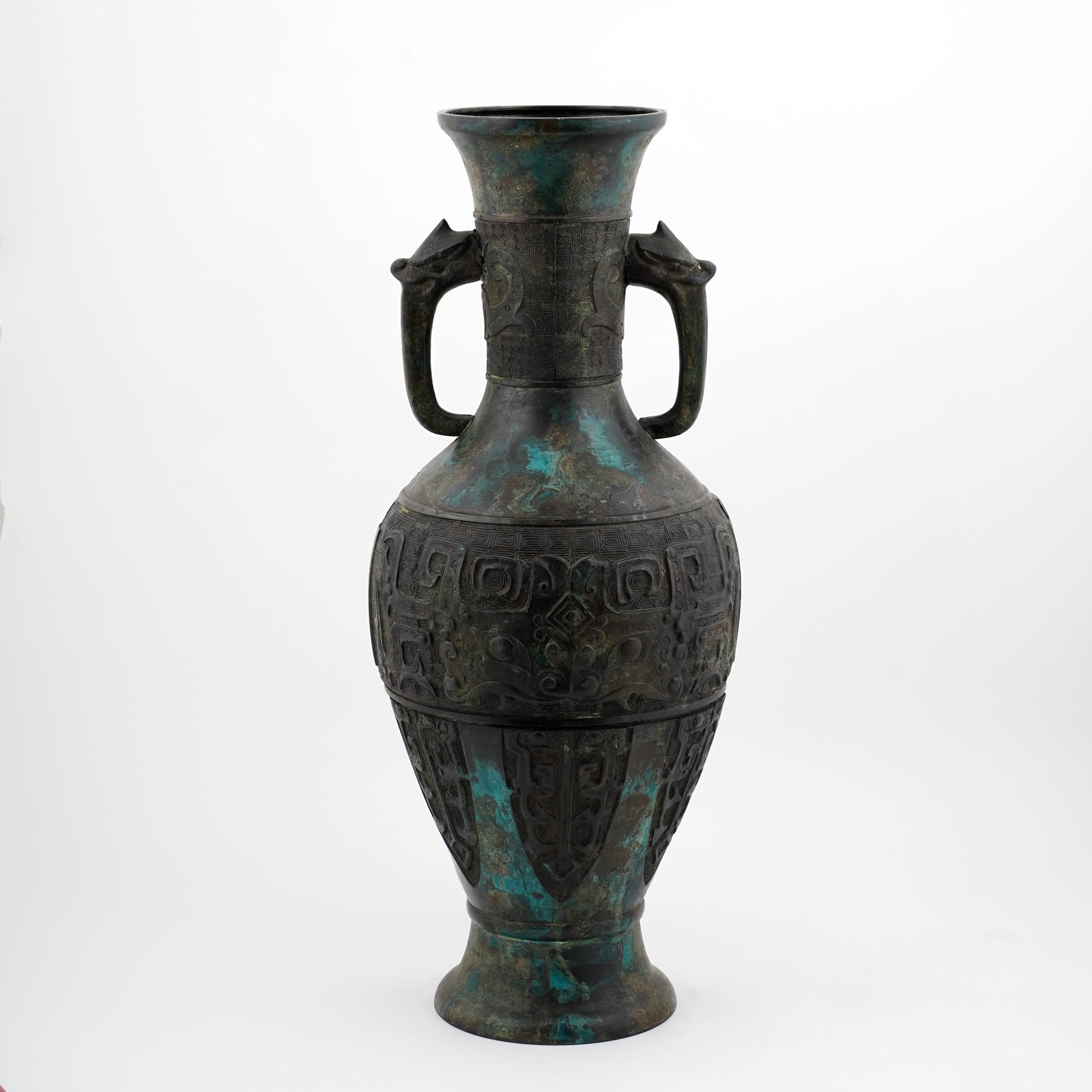 Large Chinese Archaistic Bronze Vase: Large Chinese archaistic bronze vase of hu-form, with flared mouth, twin loop handles issuing from animal-mask terminals, and raised taotie-style and geometric decoration to the neck and body. Dark pa