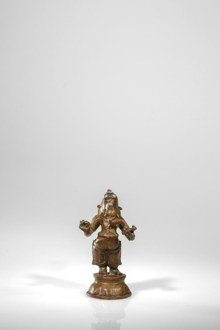 STANDING GANESHA: Bronze with Silver inlays India, 18th century or earlier Dimensions: Height 12 cm Wide 6 cm Depth 5 cm Weight: 523 grams Small statue of a standing Ganesha on round lotus base wearing a long dhoti. Th