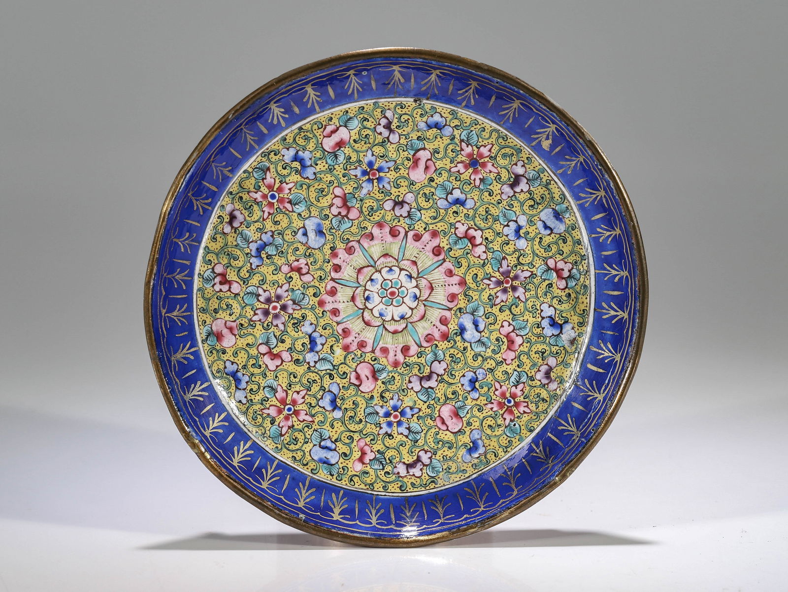 SMALL DISH: Canton-emaille China 18th - 19th century Dimensions: Height 2 cm Width 13 cm Depth 13 cm Weight: 76 grams Small round dish on three feet. Golden lip with blue rim decorated with golden ornaments. The