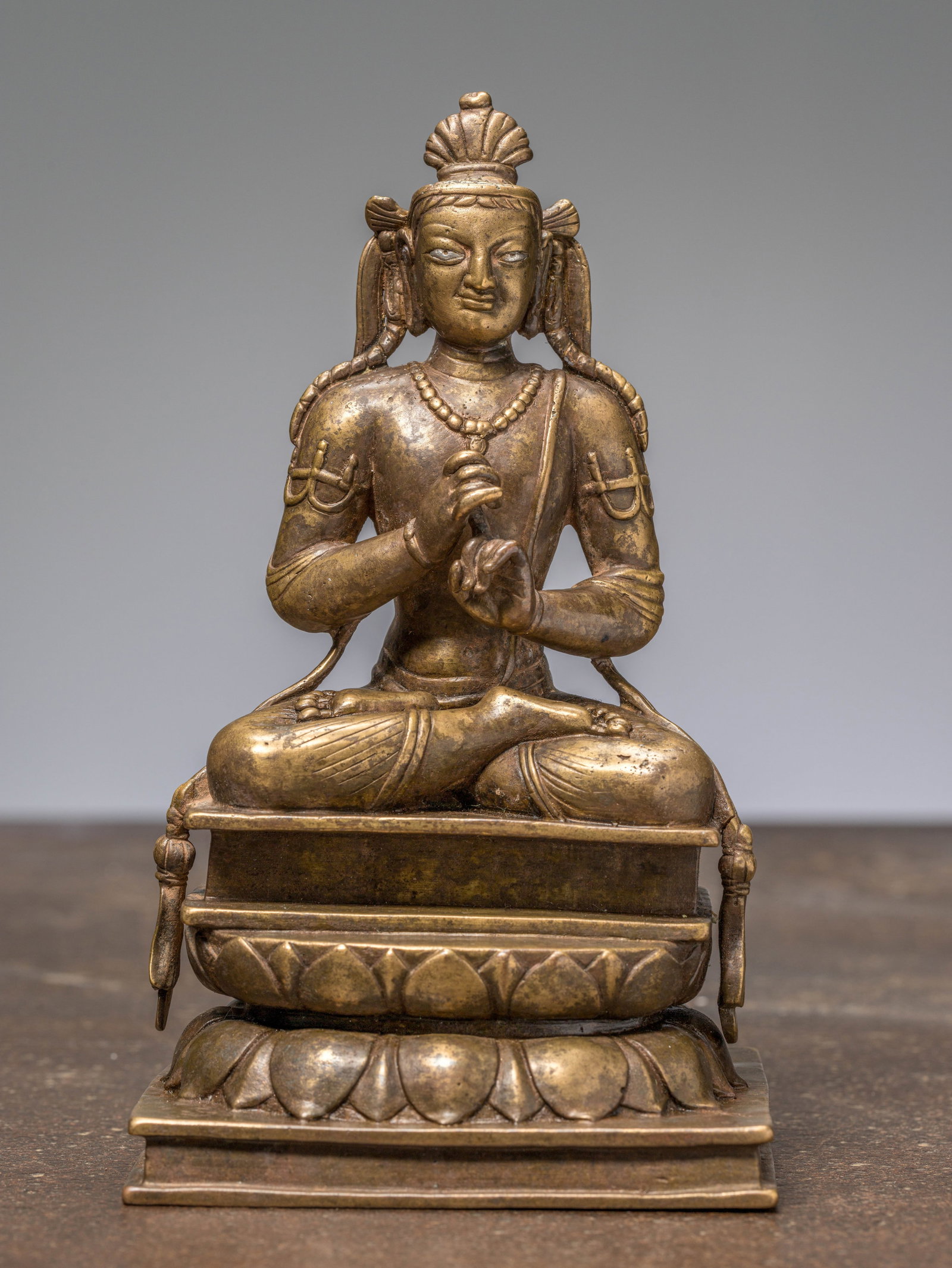A SEATED BODHISATTVA, BRONZE WITH SILVER EYES, KASHMIR, 12TH CENTURY: Dimensions: Height 19,5 cm Wide 11 cm Depth 9,5 cm Weight: 1664 grams The cast bronze figure depicts a seated bodhisattva, likely
