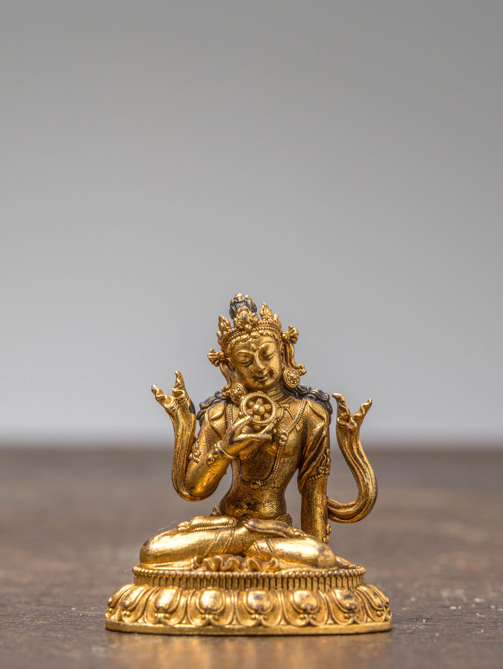 A SMALL GILT-BRONZE SEATED BODHISATTVA, TIBET OR CHINA, 18TH-19TH CENTURY: Dimensions: Height 3,6 cm Wide 3 cm Depth 2 cm Weight: 16,6 grams Finely cast in gilt bronze, the figure is depicted seated in vajr?sana on a d