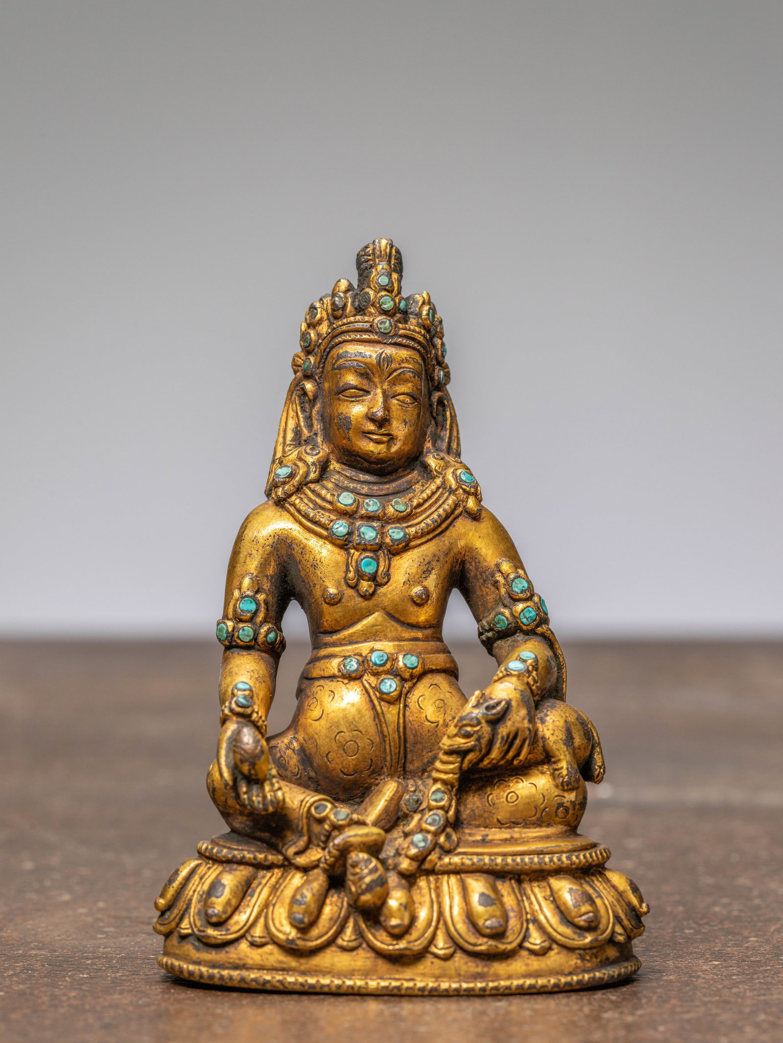 A SEATED BRONZE GILT JAMBHALA WITH TURQUOISES, TIBET, 18TH CENTURY: Dimensions: Height 11,4 cm Wide 7,5 cm Depth 6 cm Weight: 503 grams This finely cast gilt bronze depicts
