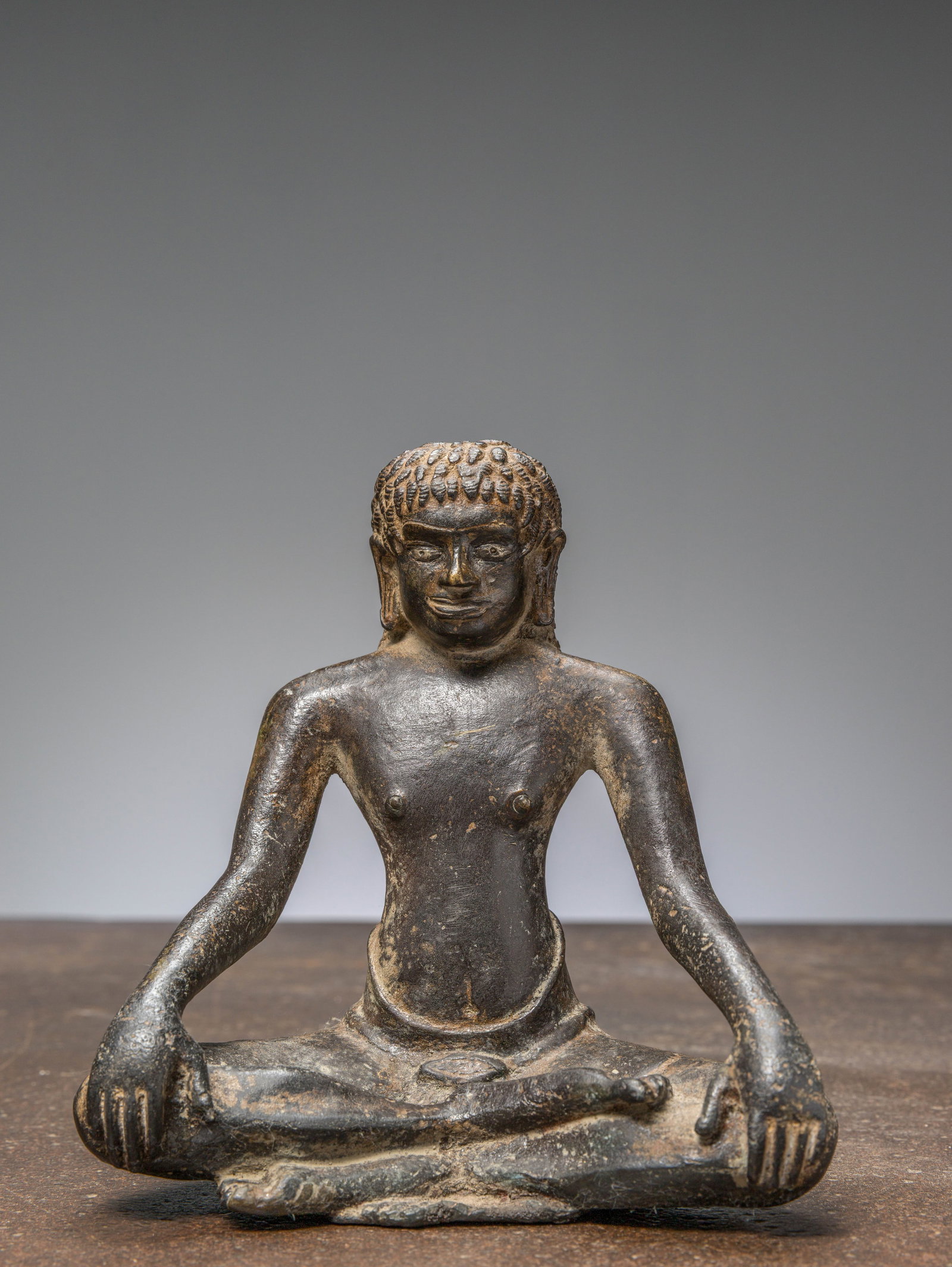A SEATED BRONZE YOGI, INDIA 12TH CENTURY, WITH SILVER EYES: Dimensions: Height 17,5 cm Wide 16,5 cm Depth 10 cm Weight: 2049 grams The figure represents a seated yogi or ascetic, shown in a meditative po