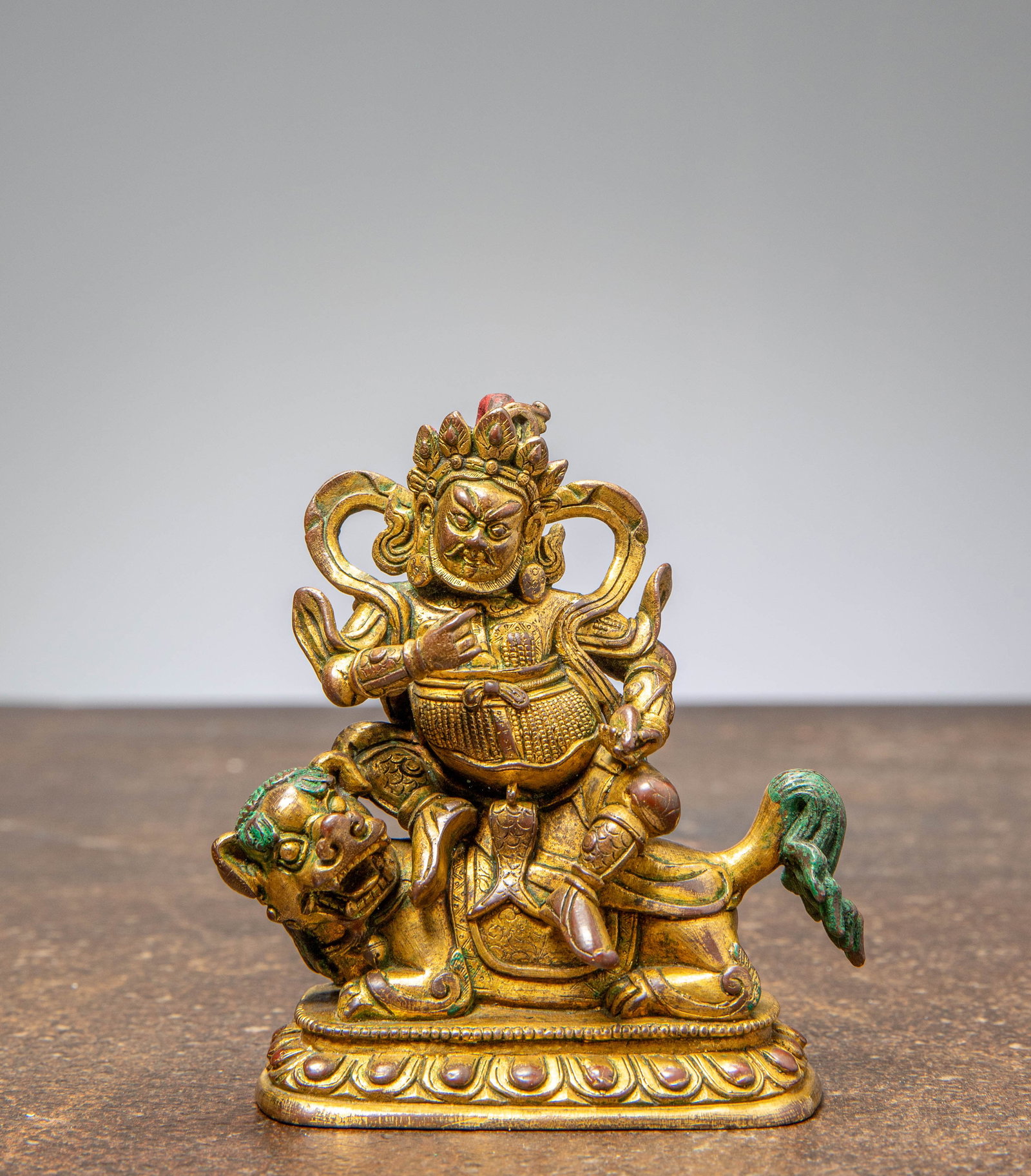 A GILT BRONZE JAMBHALA, CHINA QING DYNASTY (1644–1911): Dimensions: Height: 10,2 cm Wide 9,1 cm Depth 4,4 cm Weight: 472,9 grams The wealth deity Jambhala is depicted seated in rajalilasana upon a lotus base supported by a crouching lion, his charact