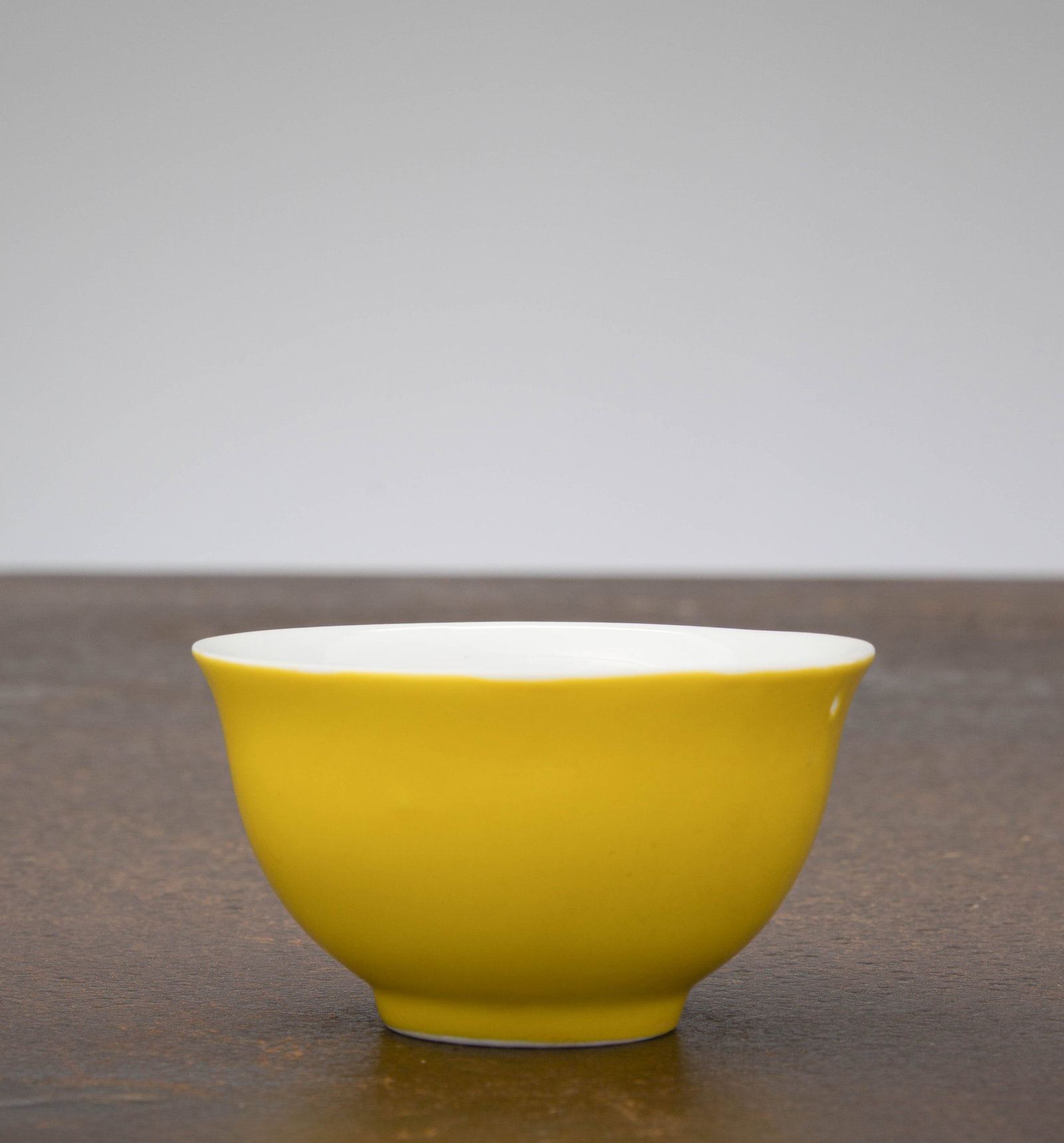 A YELLOW-GLAZED CUP, CHINA; KANGXI PERIOD (1662–1722): Dimensions: Height 4,6 cm Wide 8,5 cm Depth 8,5 cm Weight: 89 grams A finely potted porcelain cup of elegant, gently flaring form, raised on a short, neatly finished foot. The exterior is cover