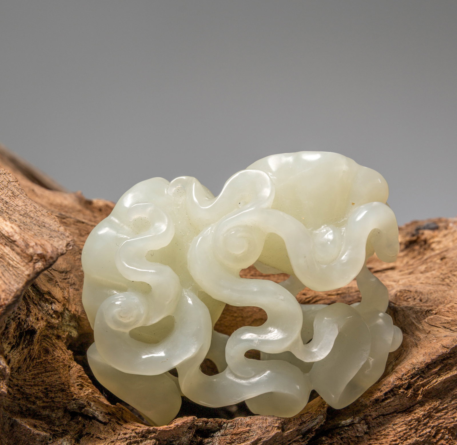 (R) A JADE IN MUSHROOM SHAPE, WHITE JADE, CHINA, 19TH CENTURY, QING DYNASTY: Dimensions: Height 3 cm Wide 6 cm Depth 4,5 cm Weight: 75,1 grams Carved as a stylised lingzhi fungus with deeply undercut, scrolling cloud-like lobes