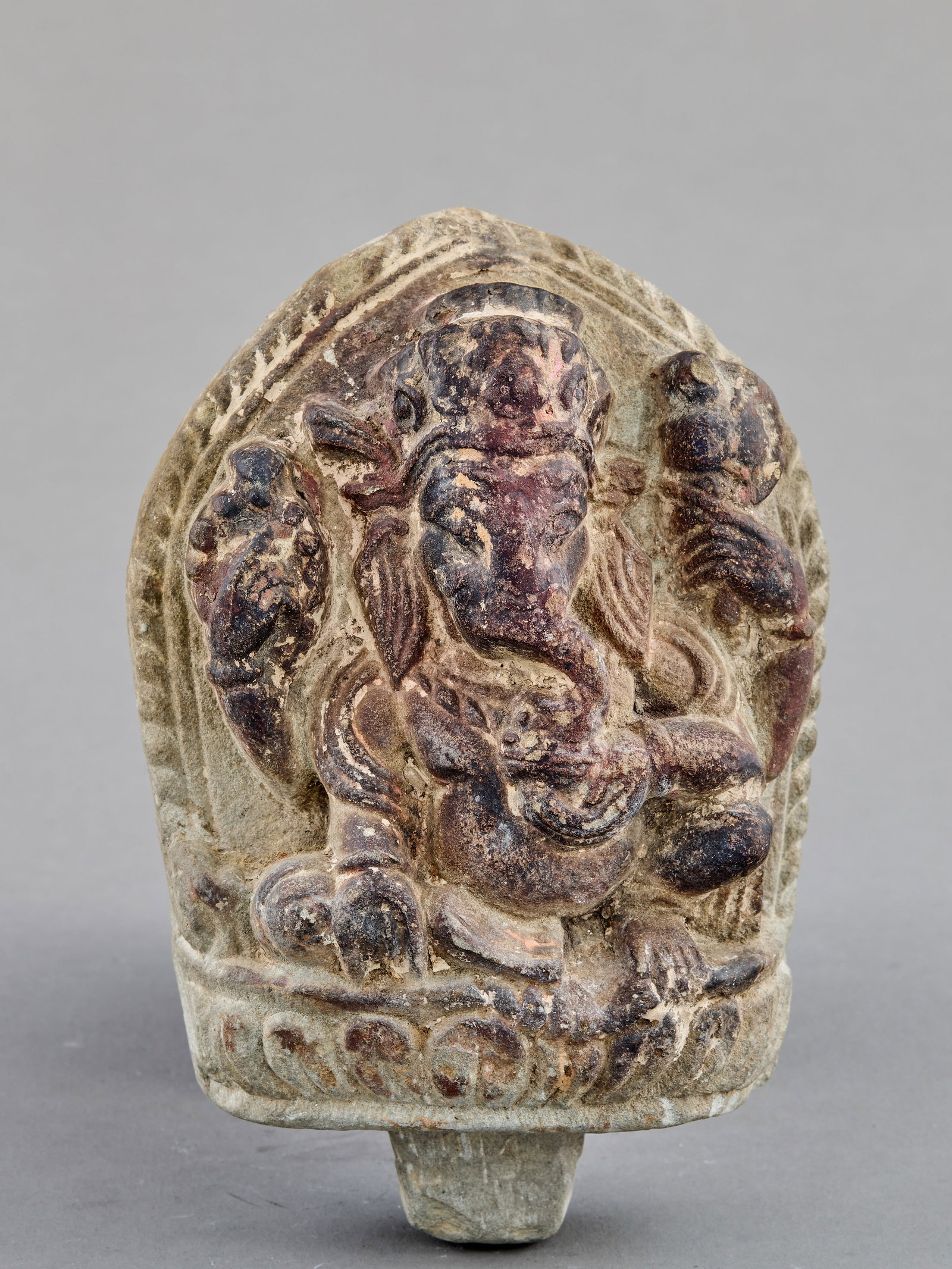 SEATED STONE GANESHA NEPAL 18TH CENTURY: Dimensions: Height 14 cm Wide 9,5 cm Depth 4,7 cm Weight: 732 grams A finely carved stone figure of Ganesha seated in lalitasana upon a lotus base within a pointed aureole. The elephant-headed