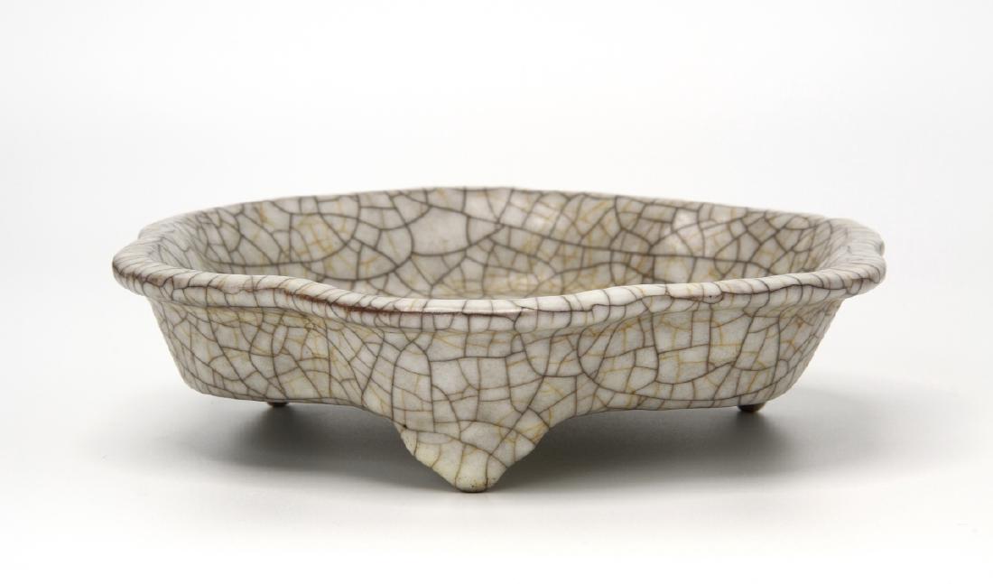 Chinese Lobed Brush Washer: Of lobed sides with flared foliate rim resting on three ruyi shaped legs, covered overall with a pale ivory glaze suffused with dark gray crackle joined by light golden crackle, 6.8 in wide. Provenanc
