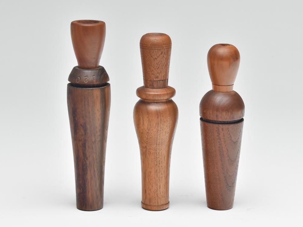 Three duck calls by various makers.: Three duck calls by various makers. One by John Ferguson, one by Penny Wade, and one by Clyde Harbin. Harbin call has "120" and "CAH" stamped at top of barrel. Longest measures 7.25". Provenance: Kirb