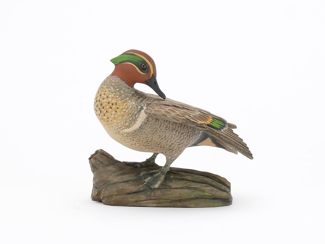 Eddie Wozny (b.1959), Cambridge, Maryland.: Miniature preening greenwing teal. On carved wooden base. Head is turned, preening one outstretched wing. Relief feather carving. Identified, signed, and dated 2004 on the underside. Measures 4" long.