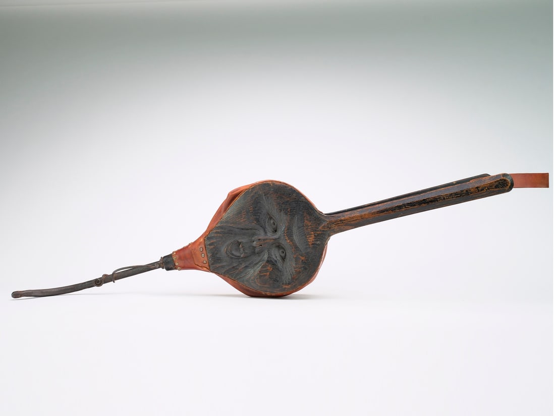 Unique carved leather and iron fireplace bellows.: Has carved face in one side and what appears to be early iron work in the shape of a snake where the air exits from. Measuring 43" long.