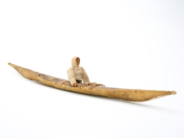 Carved Inuit eskimo in seal skin kayak, circa 1900.