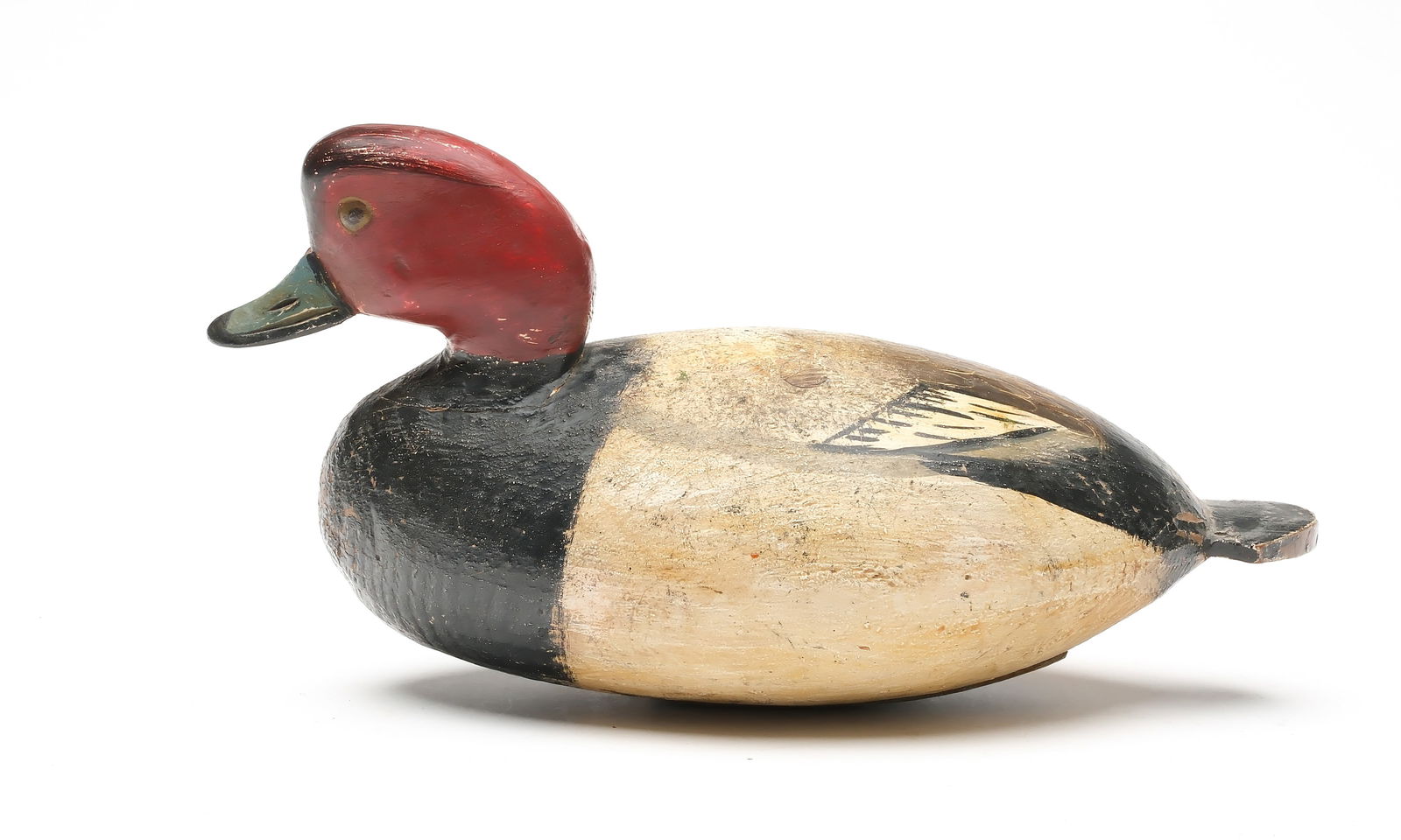 Ira Hudson (1873-1949), Chincoteague, Virginia.: Extremely rare redhead. Football body style with paddle tail and partially inlaid neck seat. Tack eyes and scratch feather paint detail on back. Measures 13.5" long. Provenance: Don Leonard collection