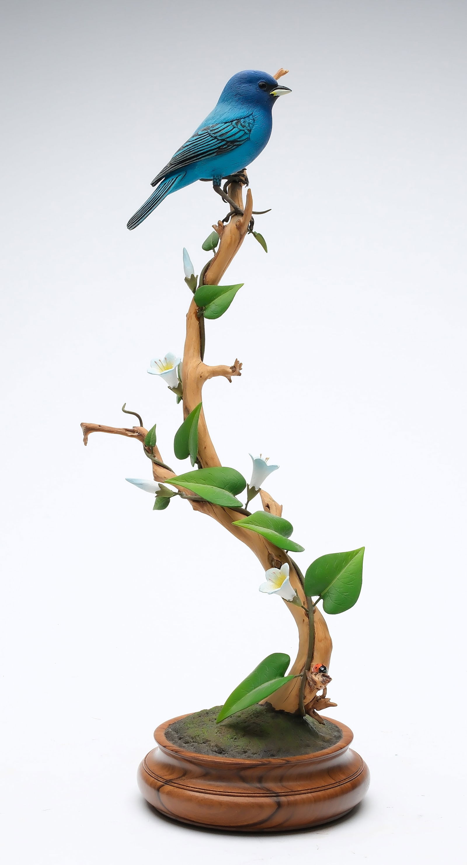 Oliver Lawson (b.1938), Crisfield, Maryland.: Decorative blue bunting and ladybug. Detailed feather carving and crossed wingtips. Signed and dated 89 on lower part of branch. Stands 15" tall.