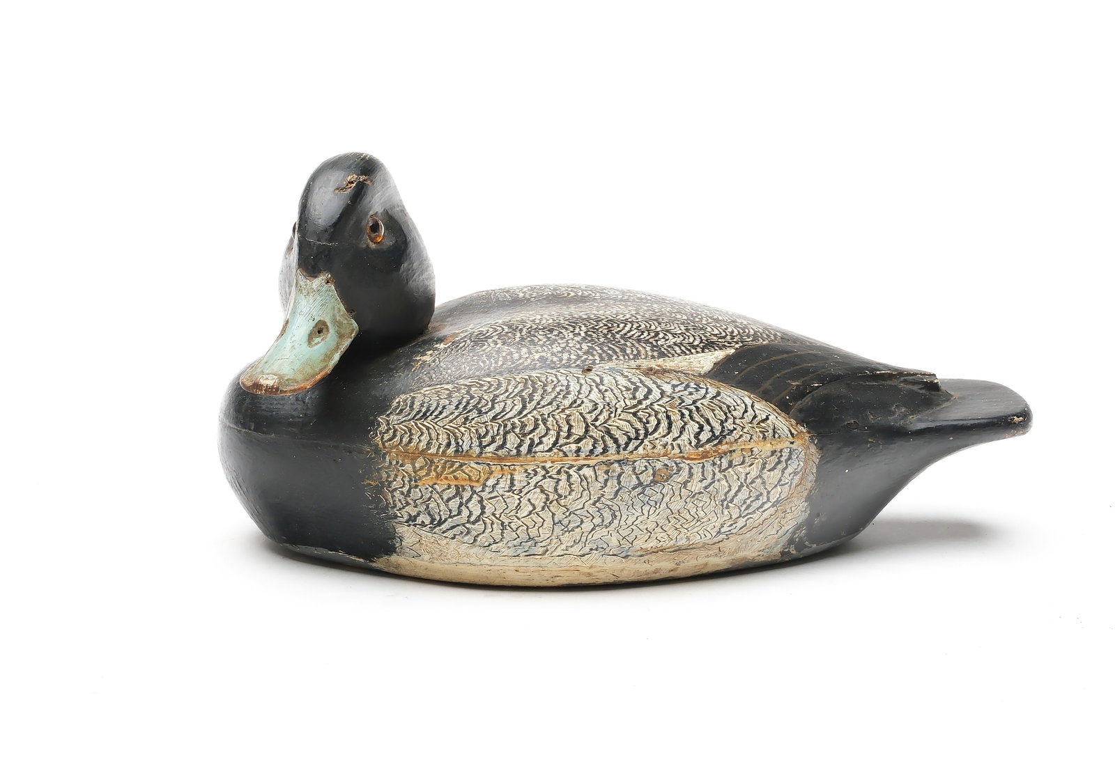 Ferd Homme (1901-1963) Stoughton, Wisconsin.: Hollow carved bluebill with head turned almost 90 degrees. Relief carved, crossed wingtips and comb feather paint detail. Measures 11.25" long. Provenance: Dr. Michael Shannahan collection.