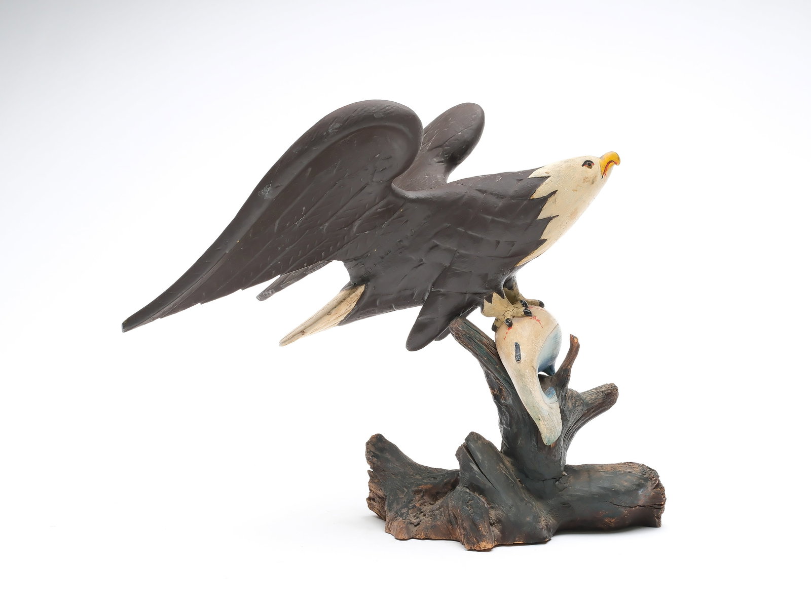 Maurice Decker (1871-1945), Dark Harbor, Maine.: Carved wooden eagle with talons grasping freshly killed fish. Carved cross hatching on eagle with carved eyes and raised wings. Decker was known for making decoys and carved eagles. Measures 10" tall.