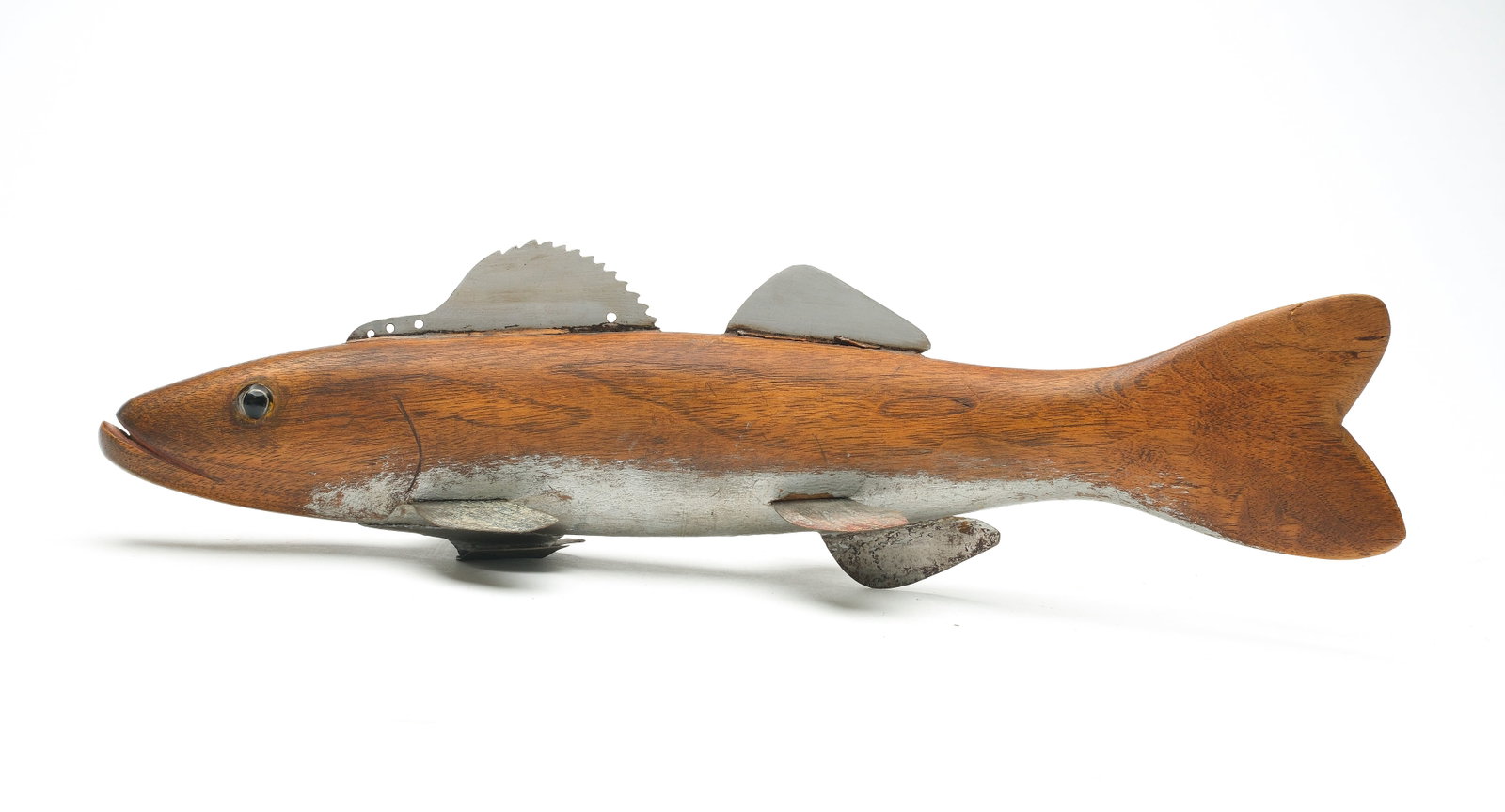 Hans Janner (1917-1985), Mt. Clemens, Michigan.: Walleye fish decoy, 1st half 20th century. Made from a piece of walnut. Glass eyes. Metal fins. Belly is painted silver. Measures 15.25" long. Provenance: Private Michigan collection.