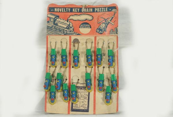 NETTE - Scarce ACTION PUZZLE Key Chain Display:: Very Collectible toys, nice display! 14" T cardboard backdrop w/15 of the original 24 chains, solving instr, sheets still attached, some wear, but nice!