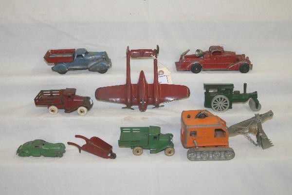 9 Pc. Toy Vehicle lot: Wyandotte P38 Airplane, red & green stake trucks. Marx Dump Truck, Wheel barrow & Coupe. Hubley Steam shovel & Fire Engine, all show heavy play wear, Minic Road Roller, functional, one wheel worn. For