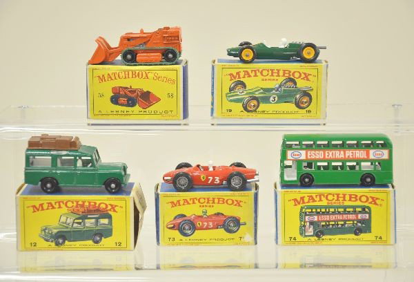 Five Boxed Matchbox Cars: #12 Land Rover in green, #58 excavator in light orange; #74 bus; #19 Lotus racer; #73 Ferrari racer. Original boxes, Land Rover box missing one flap. Excavator shows minor wear. C8. Otherwise, C9-10