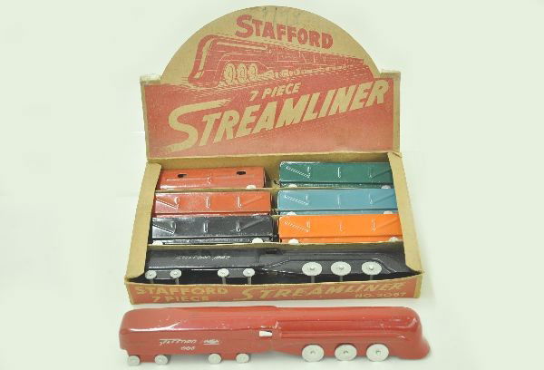 Boxed Stafford #2067 Floor Train Plus: Includes 7 piece freight train with a 13" loco tender, 5 gondolas and caboose, scarce but worn, original set box, plus and additional red locomotive tender. Shows light playwear, C8. Unusual.