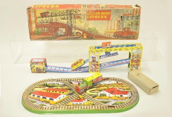 Two Unusual Platform Toys: Marx Shuttlin' Choo-Choo which includes a steam loco and freight car, mechanism functional. Trains have original box. Beautiful lithographed platform 21" long; Technofix Silvermine Express, litho tin 