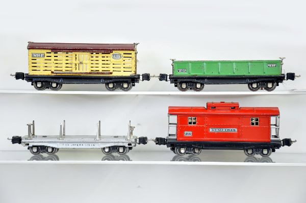 Lionel 2800 Series Cars: 2811 lumber, missing load; 2812 gondola with one split drum; 2813 stock car, missing journal box; 2817 caboose. All have 1938 couplers. Shows moderate playwear. C6