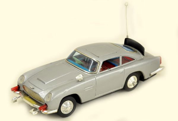 AC Gilbert James Bond Aston Martin: Litho tin and plastic, 11 1/2" long, battery operated, mechanism is functional with lighted machine guns, bulletproof shield, stop and go action, missing ejecting figure and one mirror. Clean and show